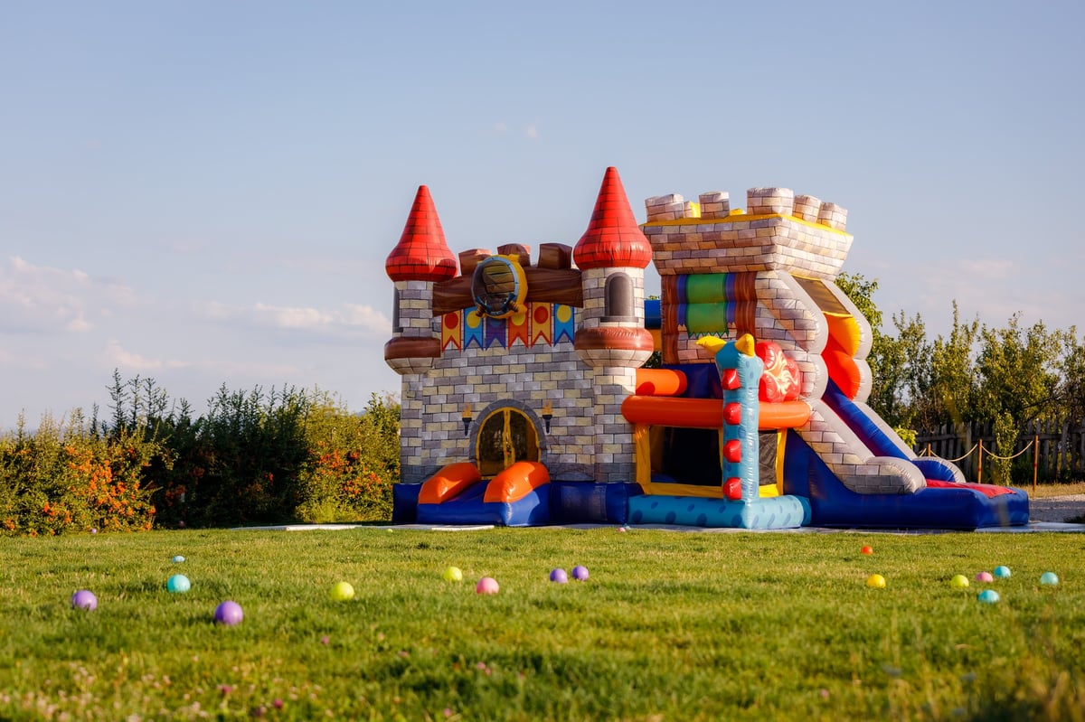 Vibrant inflatable castle bounce house in lush green field under blue sky